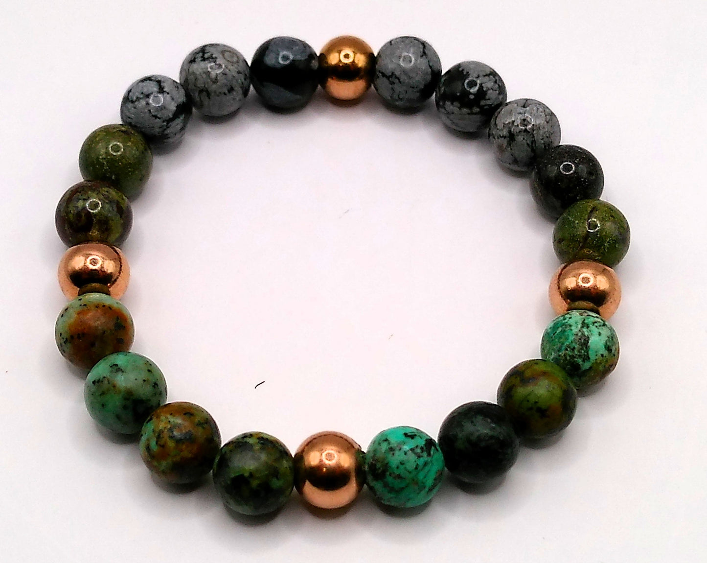 Beaded bracelet with green, black, and copper beads on a white background