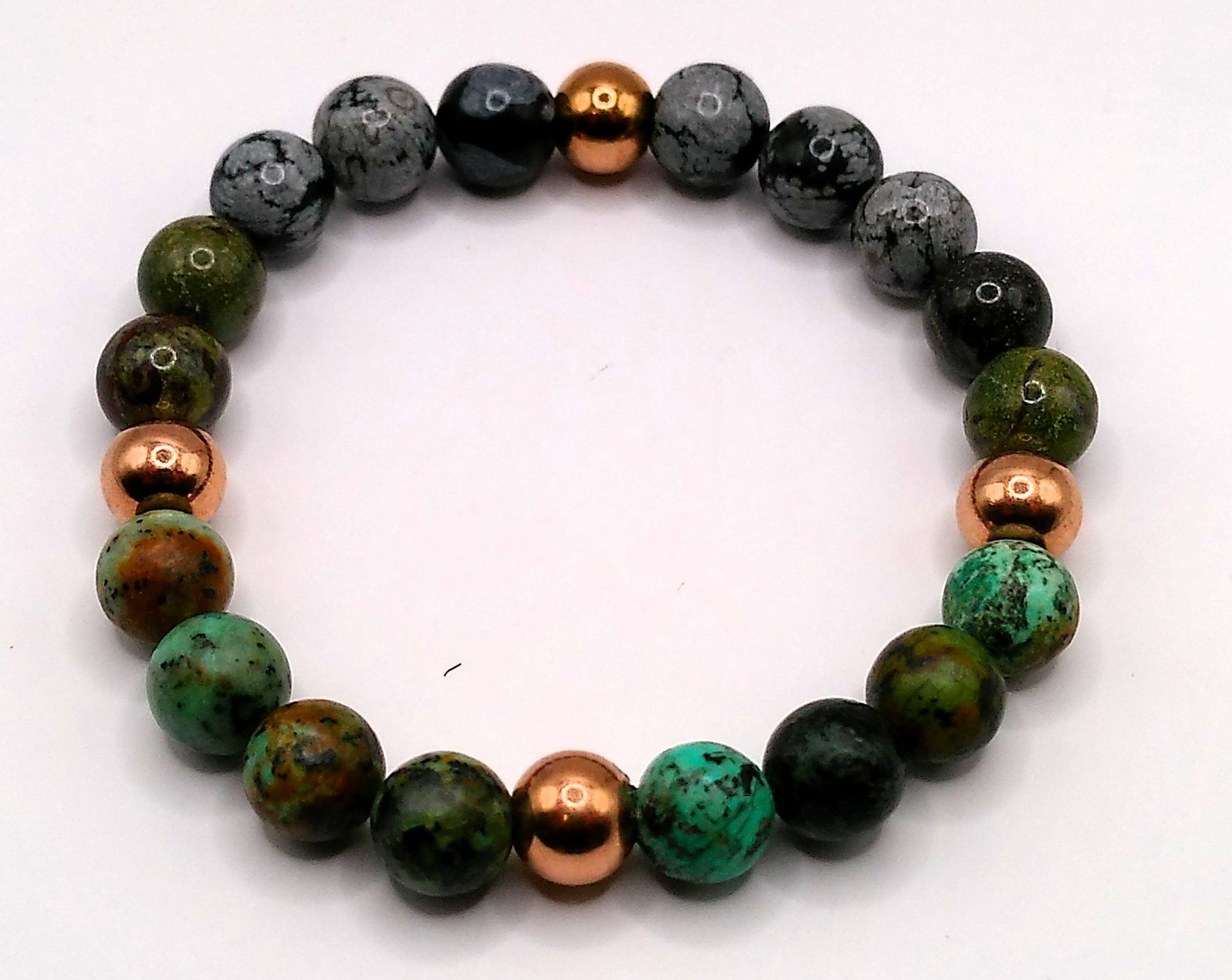 Beaded bracelet with green, black, and copper beads on a white background