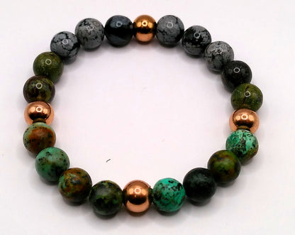 Beaded bracelet with green, black, and copper beads on a white background